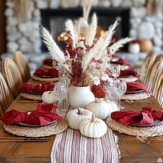 a dining room table is set with white pumpkins and red napkins