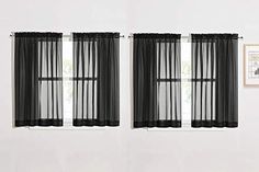 two black sheer curtains hanging on the side of a white wall next to a window