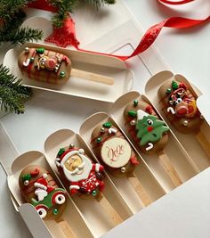 decorated cookies in boxes on a table with red ribbon and decorations around them, including santa's sleigh ornament