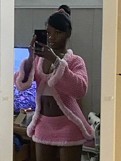 a woman is taking a selfie in the mirror with her cell phone while wearing a pink sweater and shorts