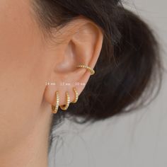 a woman's ear is shown with two small gold hoops