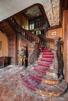 an ornate staircase with red carpet and wooden handrails