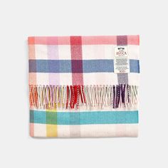 a multicolored plaid blanket with fringes on the bottom and an inscription above it