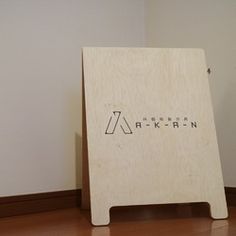 a wooden sign sitting on top of a hard wood floor next to a white wall