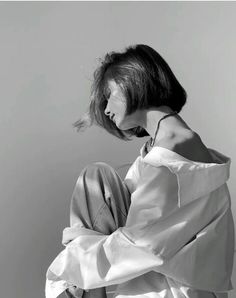 a black and white photo of a woman sitting on the ground with her head in her hands