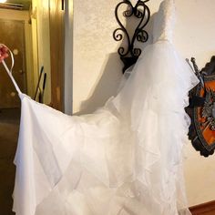 a wedding dress hanging on a wall next to a coat rack with a clock attached