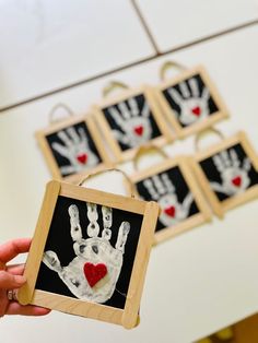 a person holding up a handprinted picture with red heart on it and six other pictures in the background