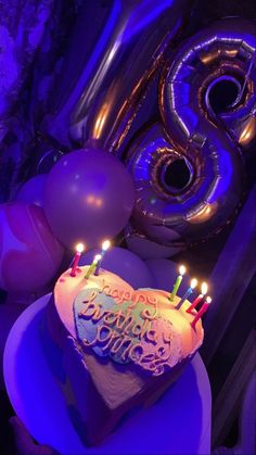 a birthday cake with candles and balloons in the background