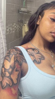 a woman with a flower tattoo on her arm looking at the camera while she brushes her teeth