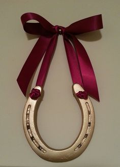 a pair of gold horseshoes tied with a red ribbon on top of a white wall