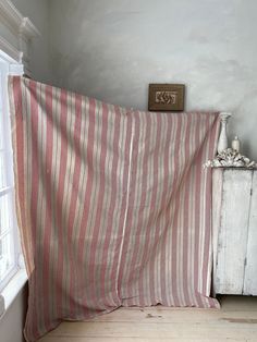 a bed with a red and white striped blanket next to a window