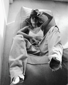 a woman sitting in a bean bag chair with her legs crossed and wearing a cowboy hat