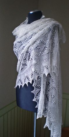 a white lace shawl on a mannequin stand in front of a wall