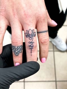 two fingers with tattoos on them, one has a cross and the other has a flower