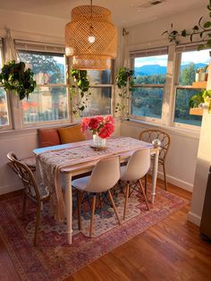 a dining room table with chairs and flowers in a vase on top of the table