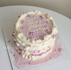 a birthday cake with white frosting and purple flowers