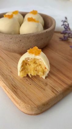 a wooden cutting board topped with three desserts next to a bowl filled with orange zest