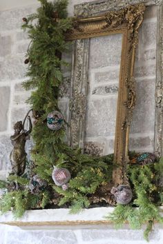 a fireplace mantel decorated for christmas with ornaments and greenery on it, in front of a mirror