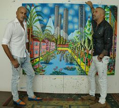 two men are standing in front of a painting