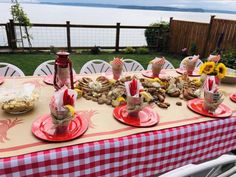 a table set up with plates, cups and food on it for a picnic by the water