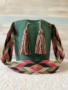 a green bucket with two tassels sitting on top of a white carpeted floor