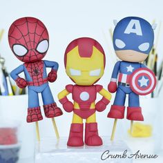 three toy figurines sitting next to each other in front of paintbrushes