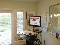 a computer monitor sitting on top of a desk in front of a map and window