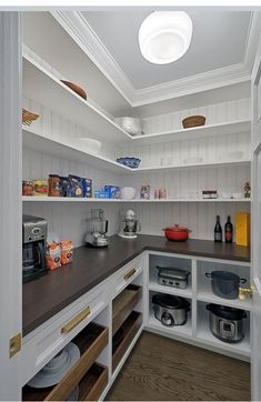 a kitchen with white cabinets and wooden counter tops in the center is filled with food items