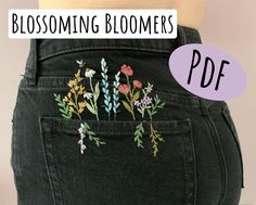 the bottom of a woman's jeans with flowers embroidered on it and text that reads, blossoming blooms