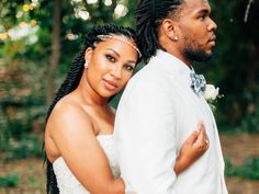 a bride and groom standing together in the woods