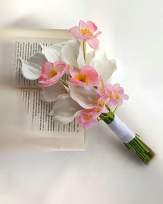 a bouquet of pink and white flowers sitting on top of an open page of a book