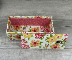 two flowered boxes sitting on top of a wooden table with one open and the other closed