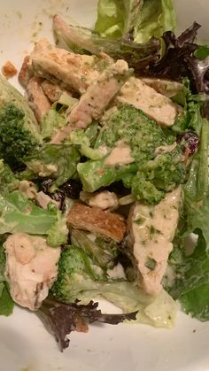 a salad with chicken and broccoli in it on a white plate, ready to be eaten