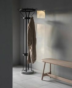 a coat rack and bench in a room with light coming through the window onto the floor