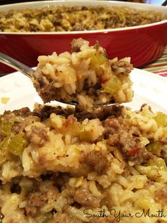 a spoonful of rice and meat casserole on a white plate with a red bowl in the background