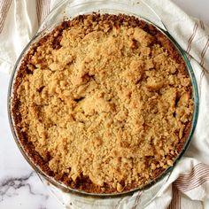 a pie sitting on top of a glass pan covered in crumbled toppings