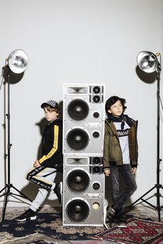 two young boys are standing next to speakers