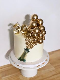 a white cake with gold decorations and a wine bottle on the top that says 30th