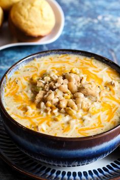 a bowl of soup on a plate next to muffins