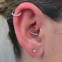 a woman's ear with two small diamond hoops