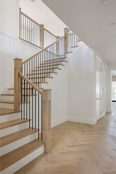 an empty room with wood floors and white walls is pictured in this image, there are stairs leading up to the second floor