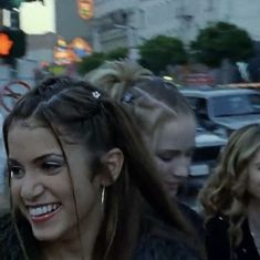 two women are walking down the street and one is holding her hair in ponytails