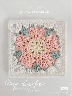 a crocheted square with a flower in the center and words written below it