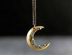 This crescent moon pendant is decorated with crushed pyrite. The pendant is suspended from a long matching necklace.Pyrite is believed to bring strong protection that shields the wearer from negative energy. The perfect addition to your crystal jewelry collection. Color: Gold Plated.Material: Crystal, Alloy. Guaranteed safe checkout:PAYPAL | VISA | MASTERCARD Shipping info:US: 4 to 7 business days.International shipping details.Available for shipping worldwide. Crescent Moon Necklace Gold, Diamond Cross Necklace Gold, Starry Night Wedding, Floating Diamond Necklace, Real Diamond Necklace, Diamond Initial Necklace, Vintage Moon, Floating Necklace, Crescent Necklace