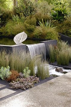 an outdoor garden with water flowing out of it's sides and plants growing on the other side