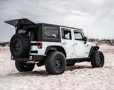 a white jeep parked on top of a sandy beach