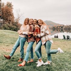 four women are posing for a photo in the grass