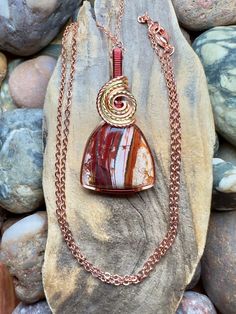 "Royal flamingo jasper/Howardite with copper, gold, and burgundy wire wrap Comes with 18\" sterling silver plated chain shown in photos.  Pendant measures 1-5/8\" x 7/8\"" Wire Wrapped Ocean Jasper Pendant Necklaces, Ocean Jasper Wire Wrapped Pendant Necklaces, Wire Wrapped Ocean Jasper Pendant Necklace, Unique Red Jasper Necklaces, Wire Wrapped Jasper Pendant Necklace, Hand-wrapped Jasper Pendant Necklace, Hand Wrapped Jasper Pendant Necklace, Spiritual Jasper Necklaces Wire Wrapped, Spiritual Jasper Necklaces With Wire Wrapped