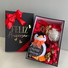 a penguin in a box with some confetti and a card for an anniversary