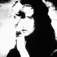 a black and white photo of a woman with her hand on her chin looking to the side